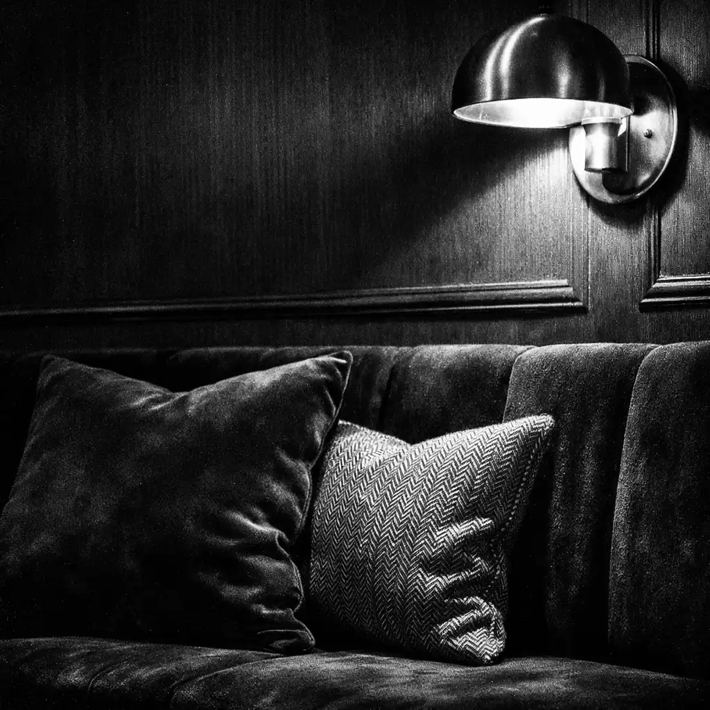 Banquette en velours noir éclairée par une applique murale en laiton